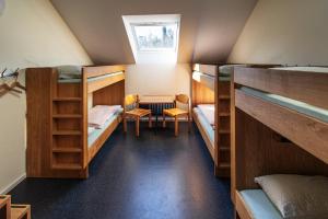 バーデンにあるBaden Youth Hostelの二段ベッド、テーブル、椅子が備わる客室です。