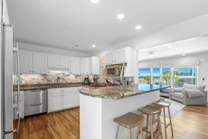 a kitchen with white cabinets and a bar with stools at Sav's Beach Pad in Pensacola Beach