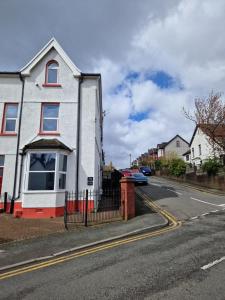 a white house with red windows on a street at 5 Bedroom modern home with parking. Near Brecon Beacons & Bike Park Wales in Merthyr Tydfil