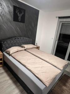 a bed in a bedroom with a gray wall at Una-No1 in Bihać
