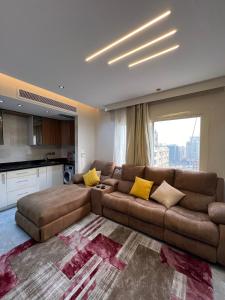 a living room with a brown couch and a kitchen at المهندسين جزيره العرب in Cairo