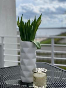 a white vase with a plant and a candle on a table at Fewo-Exklusiv "Seeblick" in Großräschen