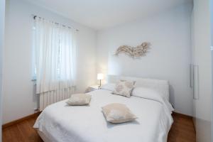 1 dormitorio blanco con 1 cama blanca y 2 almohadas en Pepi apartment with terrace, en Ičići