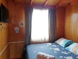 um pequeno quarto com uma cama e uma janela em Hospedaje Familiar Doña Juanita em Puerto Montt