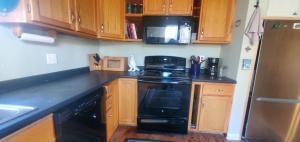 cocina con armarios de madera y estufa negra en Blue Ridge Chalet chalet en Mendon