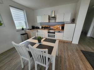 uma cozinha com mesa e cadeiras e uma cozinha com armários brancos em Fewo-Exklusiv "Hafenkante" em Grossräschen