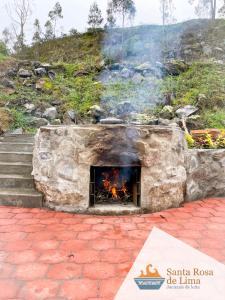a stone fireplace with a fire in it at Santa Rosa de Lima Hostal Zuleta in Zuleta