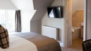 a bedroom with a bed with a tv on the wall at The Pavilion Bisley in Bisley
