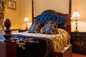 a bedroom with a bed with a blue headboard and pillows at Harrisons Hall Bed & Breakfast in Mold