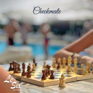 a person playing a game of chess on a chessboard at Le Six Hotel And Resort in Batro&ucirc;n