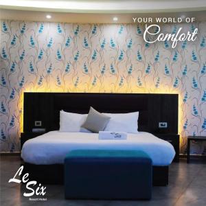バトゥルーンにあるLe Six Hotel And Resortのベッドルーム1室(青い花の壁にベッド1台付)