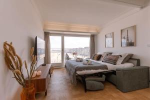 een slaapkamer met een bed, een bank en een raam bij Stunning studio with sea-view and terrace in Knokke-Heist