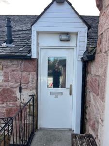 un perro está parado detrás de una puerta blanca en The Mews Holiday Let, en Tillicoultry