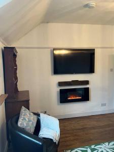 een woonkamer met een open haard en een televisie bij The Mews Holiday Let in Tillicoultry