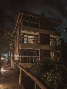 an apartment building at night with a wooden walkway at Refugio dos Guaias in Bombinhas