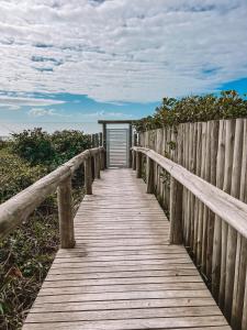 a wooden boardwalk leading to a door on the beach at Refugio dos Guaias in Bombinhas