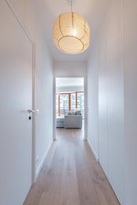 un pasillo vacío con puerta y una habitación con sofá en Comfortable apartment near the sea en Knokke-Heist