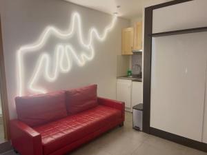 a red couch in a kitchen with a neon sign on the wall at Le Néon Dijonnais in Dijon