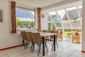 - une salle à manger avec une table, des chaises et des fenêtres dans l'établissement Bohemien Resort 8, à Sint Maartensvlotbrug