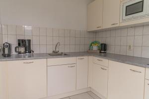 - une cuisine blanche avec des placards blancs et un évier dans l'établissement Bohemien Resort 8, à Sint Maartensvlotbrug