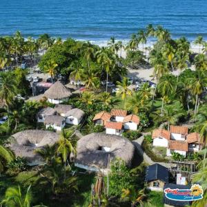 una vista aérea de un complejo con palmeras y el océano en Casa Grande Surf en Guachaca