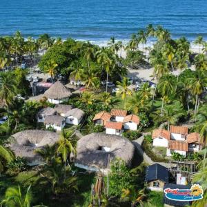 una vista aérea de un complejo con palmeras y el océano en Casa Grande Surf, en Guachaca