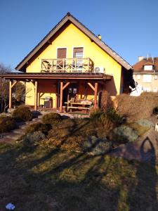 ein gelbes Haus mit einer Veranda und einer Terrasse in der Unterkunft NOCLEGI u ANI in Otmuchów