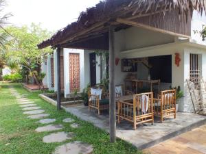 une petite maison avec des chaises et une terrasse couverte dans l'établissement Home Farm Villa Hoi An, à Hội An