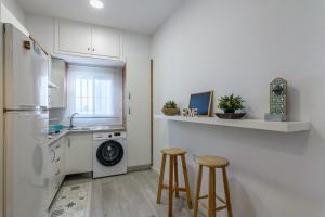 una cocina con lavadora y secadora y 2 taburetes en El Estudio del Astillero, en Ayamonte