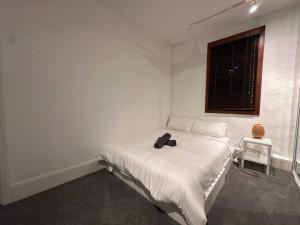 a white bedroom with a bed with a black bag on it at Remarkable 2 Bedroom House at the Centre of Darlinghurst in Sydney