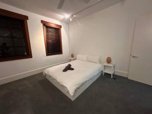 sypialnia z białym łóżkiem z kapeluszem w obiekcie Remarkable 2 Bedroom House at the Centre of Darlinghurst w mieście Sydney