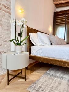 ein Schlafzimmer mit einem Bett und einem Tisch mit Blumen darauf in der Unterkunft Palazzo CarpeDiem-Prato della Valle in Padua