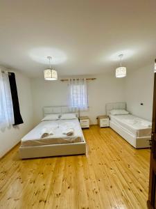 2 letti in una camera con pavimenti in legno di Mountain Oasis a Valbona