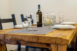 einen Holztisch mit Gläsern und eine Flasche Wein in der Unterkunft Casa Graziosa in Campodolcino