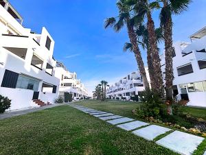 una calle con palmeras y edificios blancos en La Luz de Alborada, en Playas de Vera