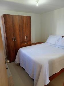a bedroom with a white bed and a wooden cabinet at Lindo Apartamento en alquiler in Rionegro