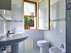 Un baño con lavabo, inodoro y ventana. en La Parapepita - Villetta con giardino privato, en Orosei 27 fotos más
