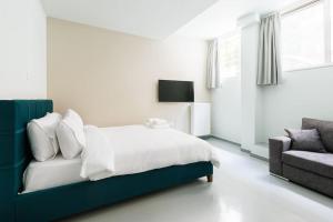 um quarto branco com uma cama e um sofá em Snug studio apartment with shared garden II em Atenas