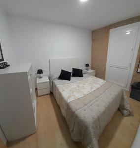 a white bedroom with two beds and two night stands at Casa MENDEZ - ALLARIZ in Ourense