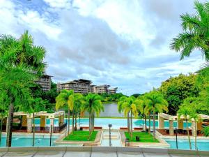 a resort swimming pool with palm trees and buildings at Miranda B 308 1BR at Pico de Loro by Raquel's Place in Nasugbu