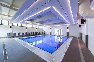 a large swimming pool with blue water in a building at Trixi Park Zittauer Gebirge - Ferienhäuser, Hotel und Camping in Großschönau