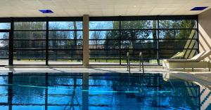 a swimming pool with two chairs and a large window at LA FOLIE in Forges-les-Eaux