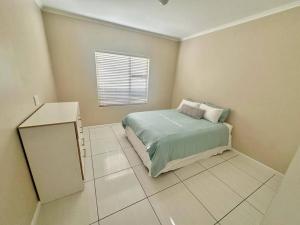 a small bedroom with a bed and a window at Coral Bliss in Walvis Bay