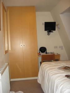 a bedroom with a closet and a bed and a tv at Americana Hotel in London