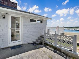 a white house with a porch and a fence at Twin Sails Brought to you by GetAway Vacations in Wells
