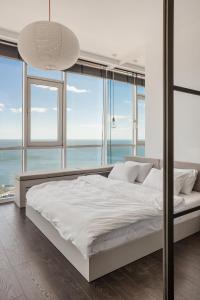 a bedroom with a large white bed with windows at Sea and Sky Apartment in Odesa