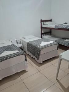 Habitación con 3 camas y suelo de baldosa. en Hotel Araçariguama en Araçariguama