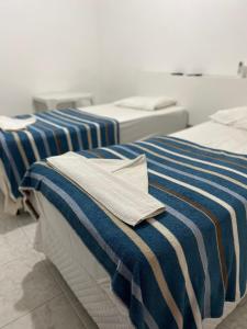 two beds with blue and white striped sheets in a room at Hotel Araçariguama in Araçariguama