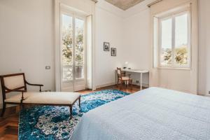 een slaapkamer met een bed, een stoel en ramen bij The Queen's Suite - Villa Candela in Stresa