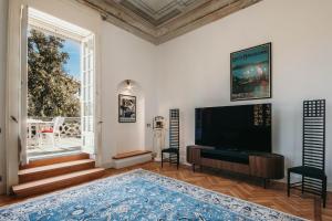 een woonkamer met een tv en een groot raam bij The Queen's Suite - Villa Candela in Stresa